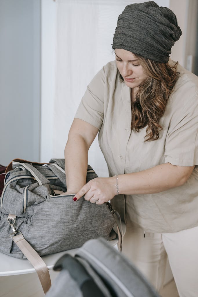 Curve woman in cap packing bag while preparing hospital bag for birthing center in southern California